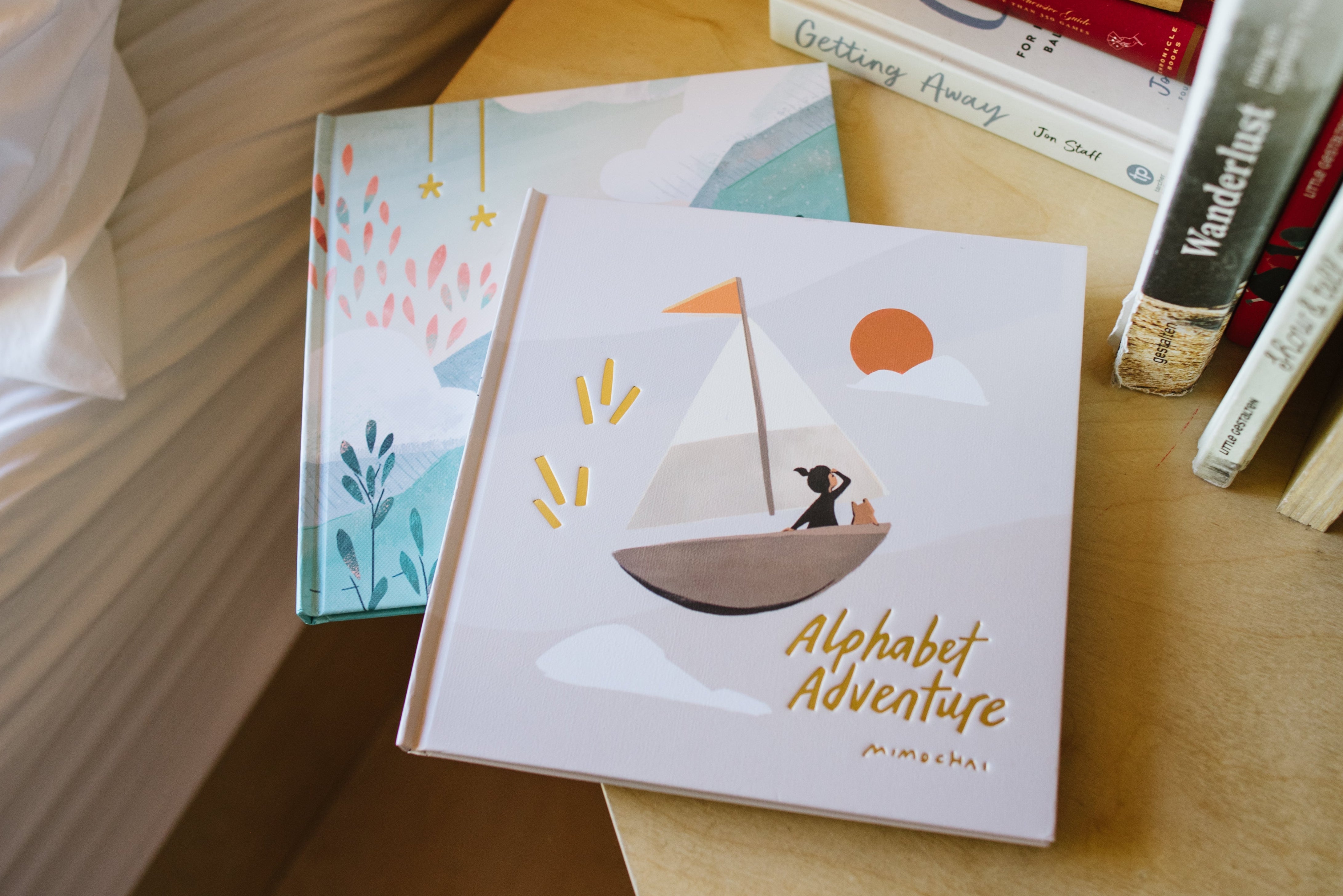 Children's book titled 'Alphabet Adventure' on a wooden surface with other books.