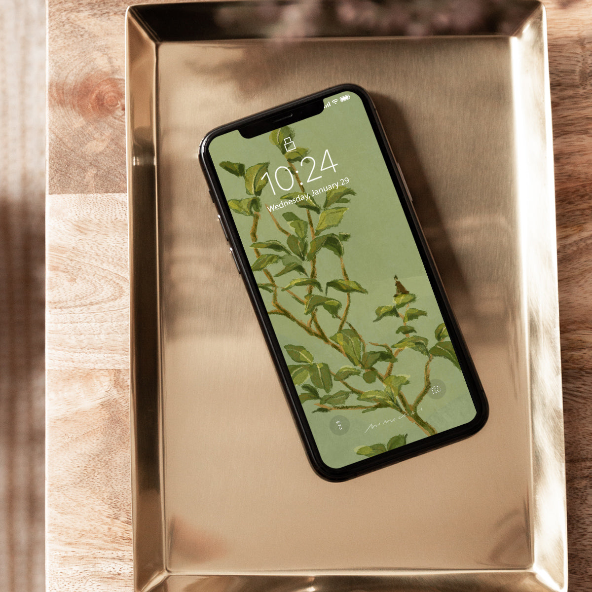 Smartphone with a green leafy pattern on the screen displayed on a metallic surface.