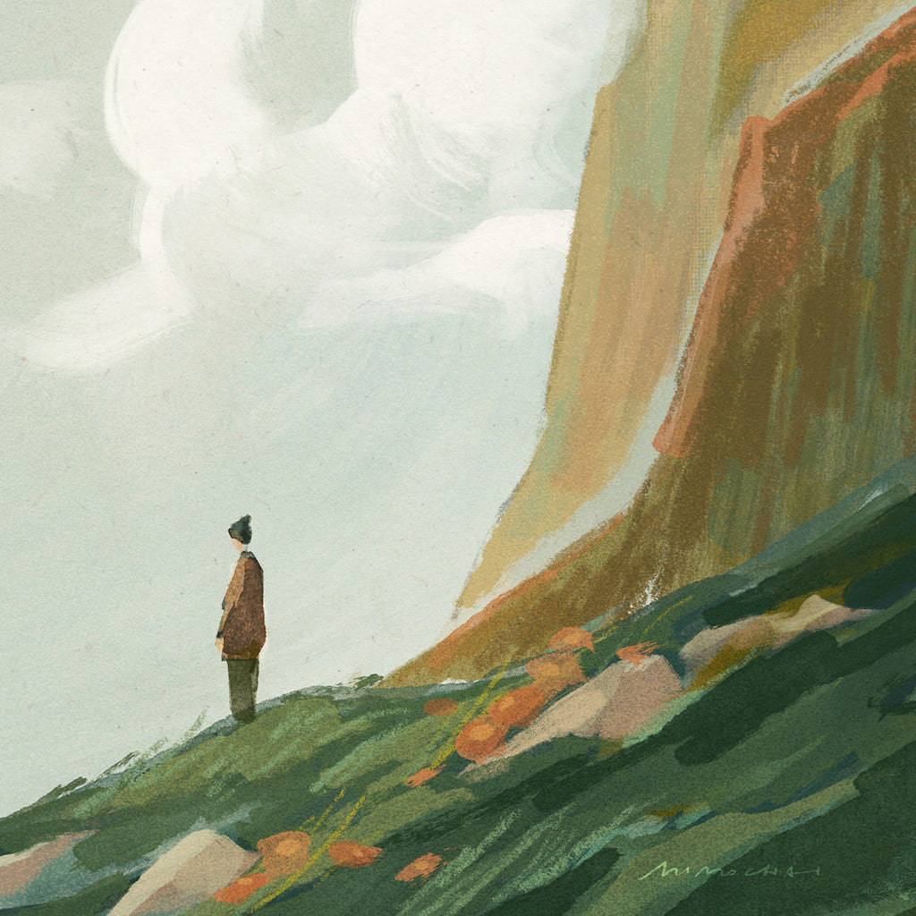Person standing on a grassy hill with a mountain and cloudy sky in the background