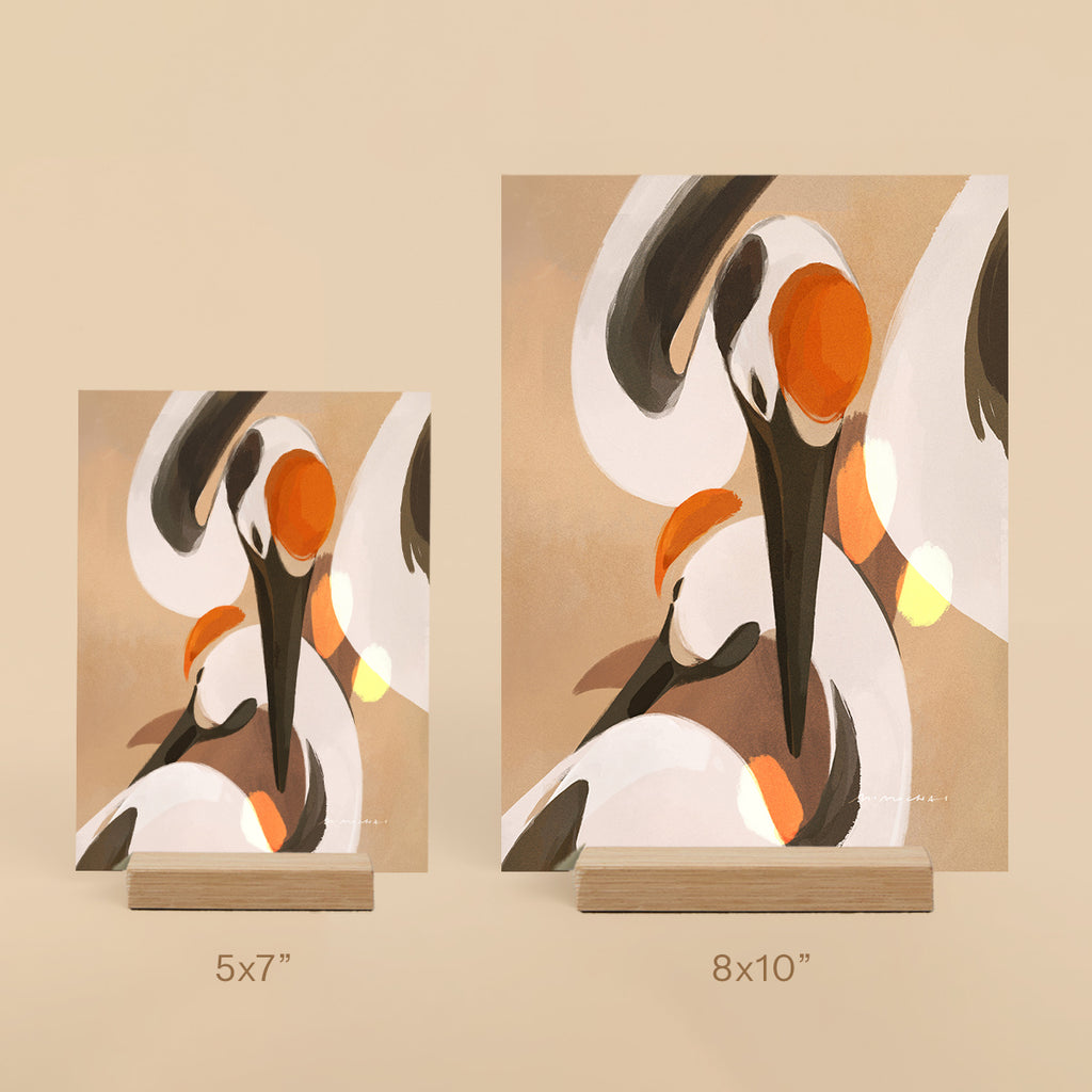 Two abstract art prints of cranes on stands with size labels on a beige background