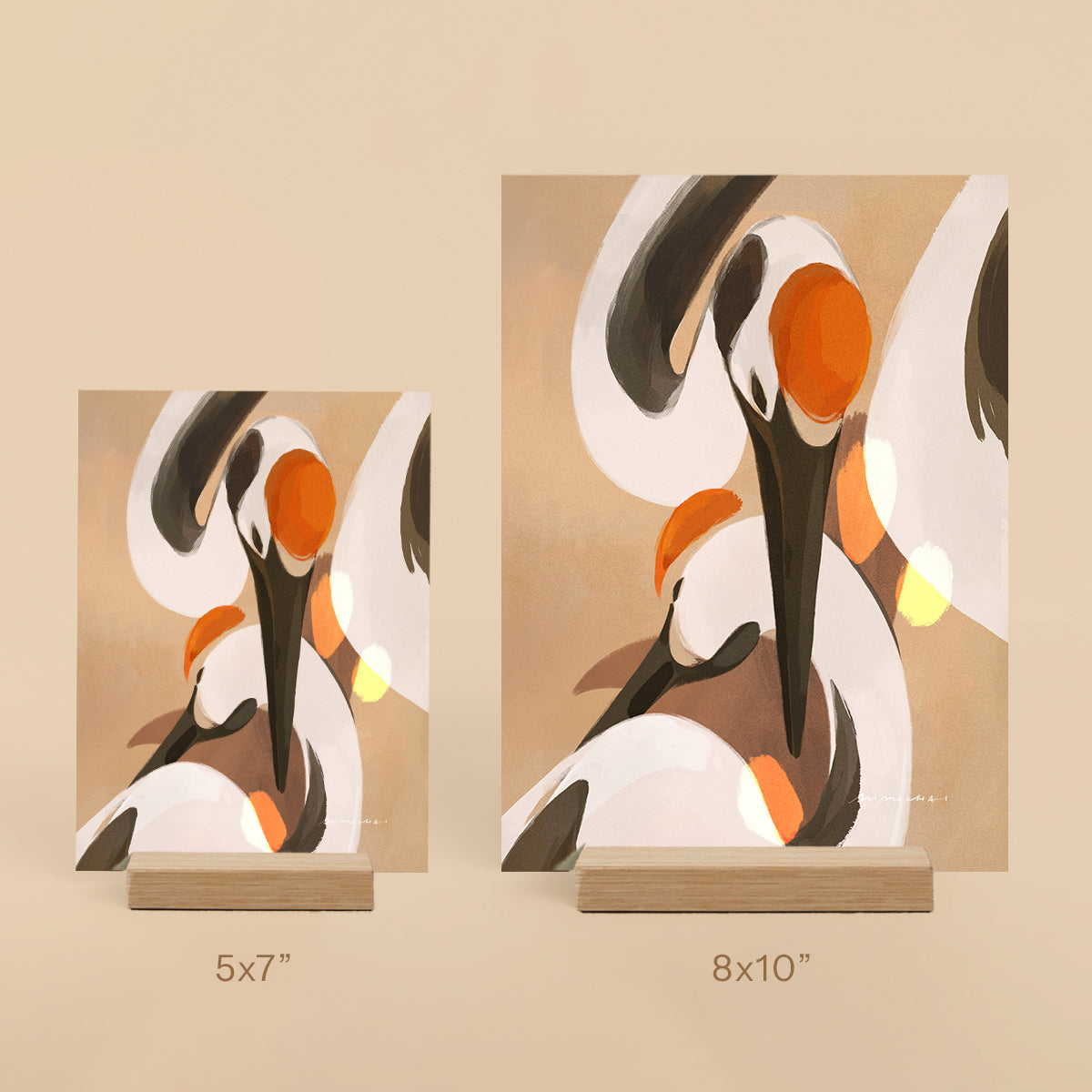 Two abstract art prints of cranes on stands with size labels on a beige background