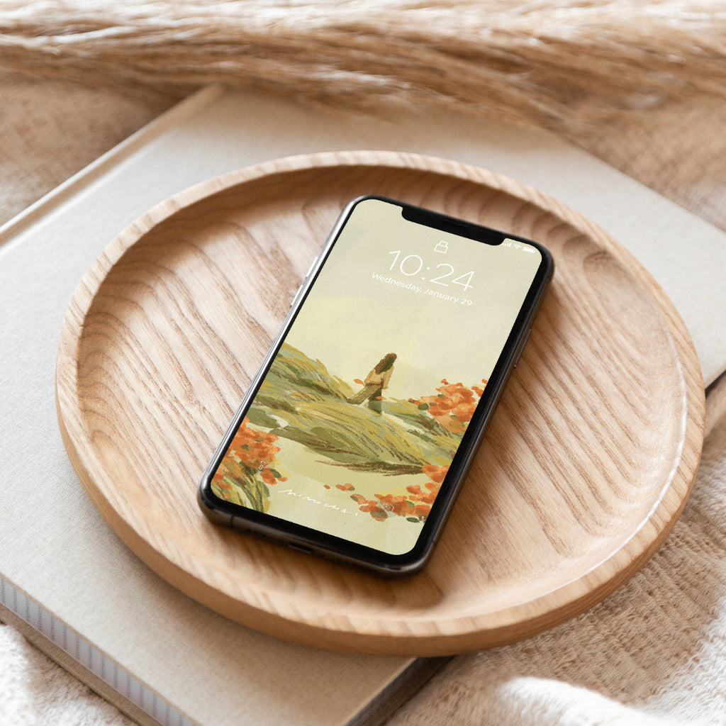 Smartphone with a scenic wallpaper of a woman in a field, on a wooden plate
