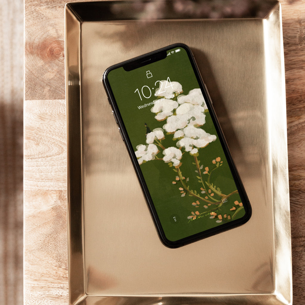 Smartphone screen with white flowers and green background on a metallic tray
