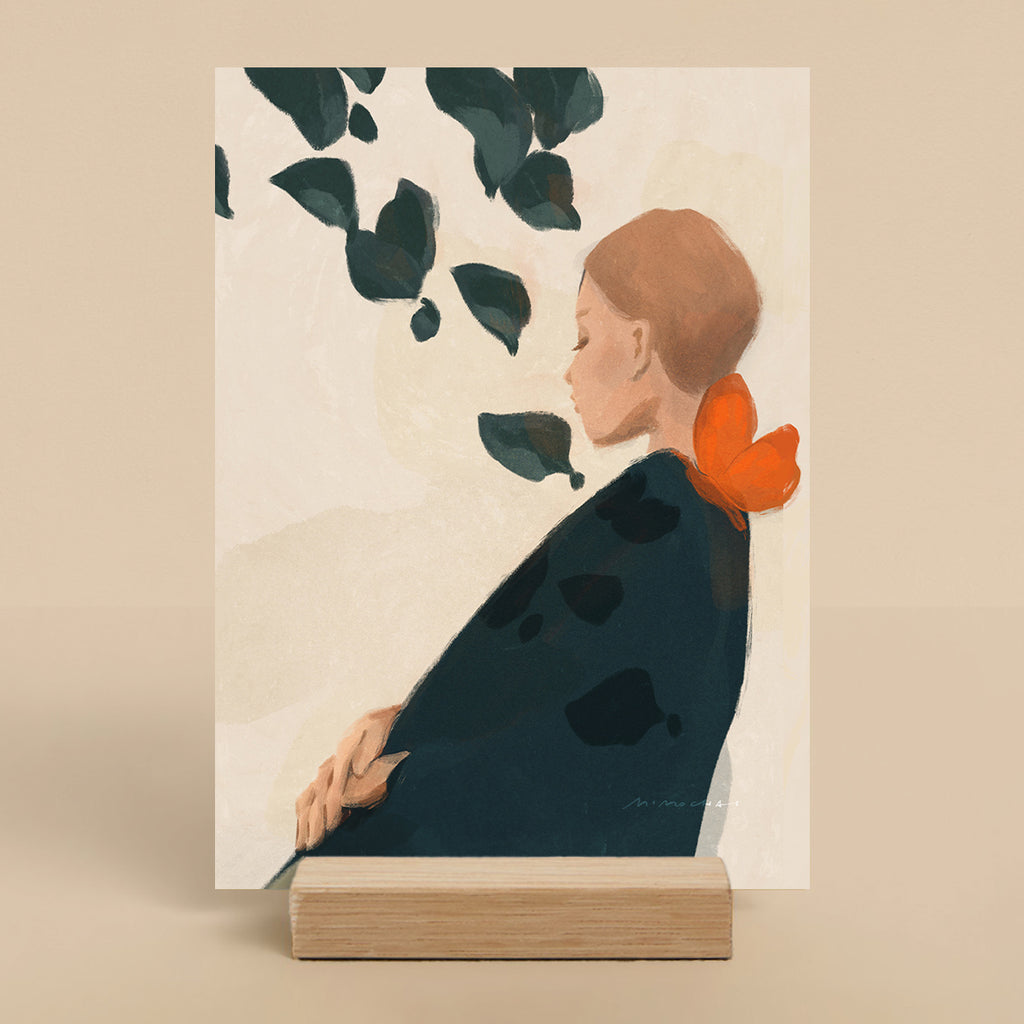 Art print of a woman with an orange butterfly on her shoulder in her hair on a beige stand.