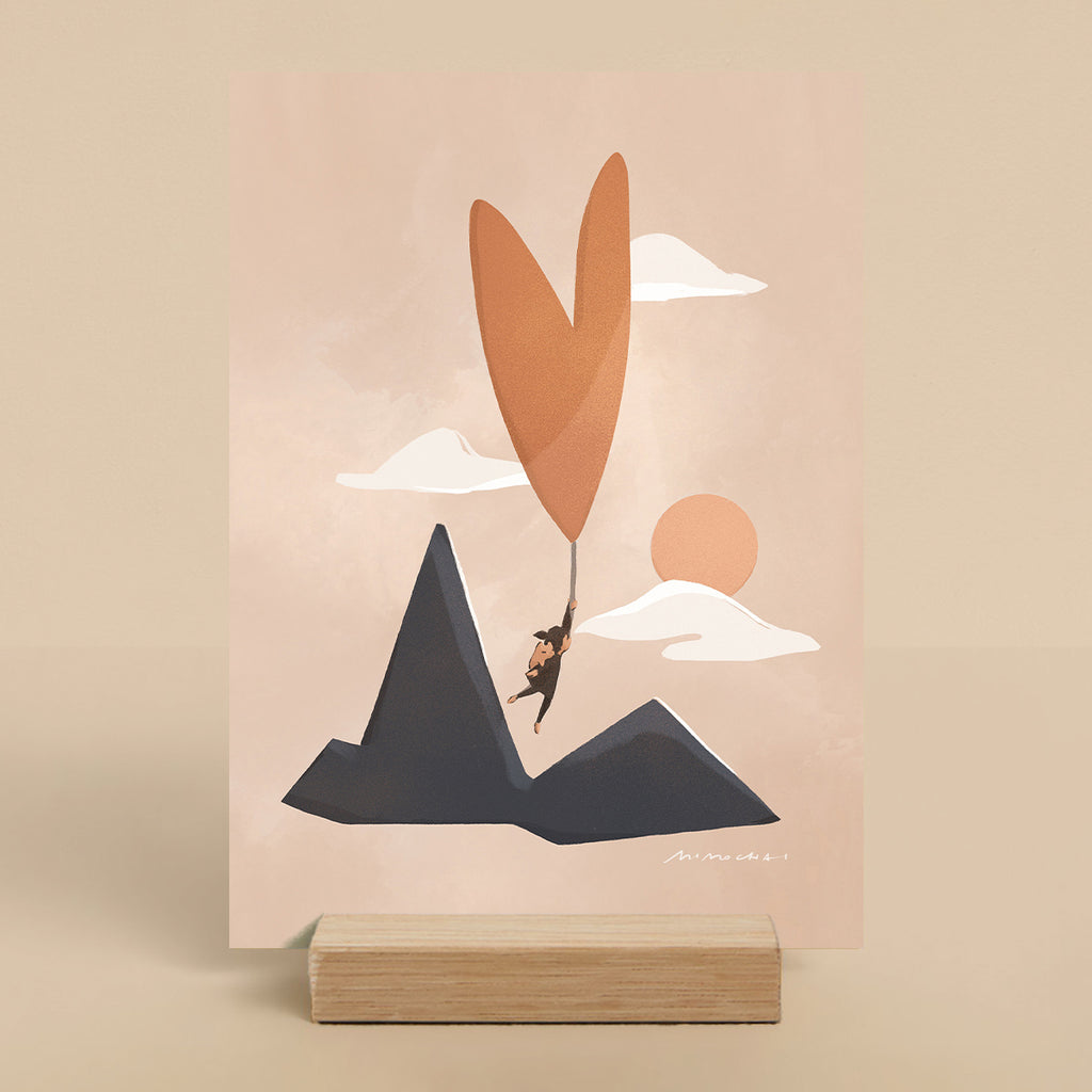 Illustrated art print with person holding heart-shaped balloon flying over mountains on a pink background.