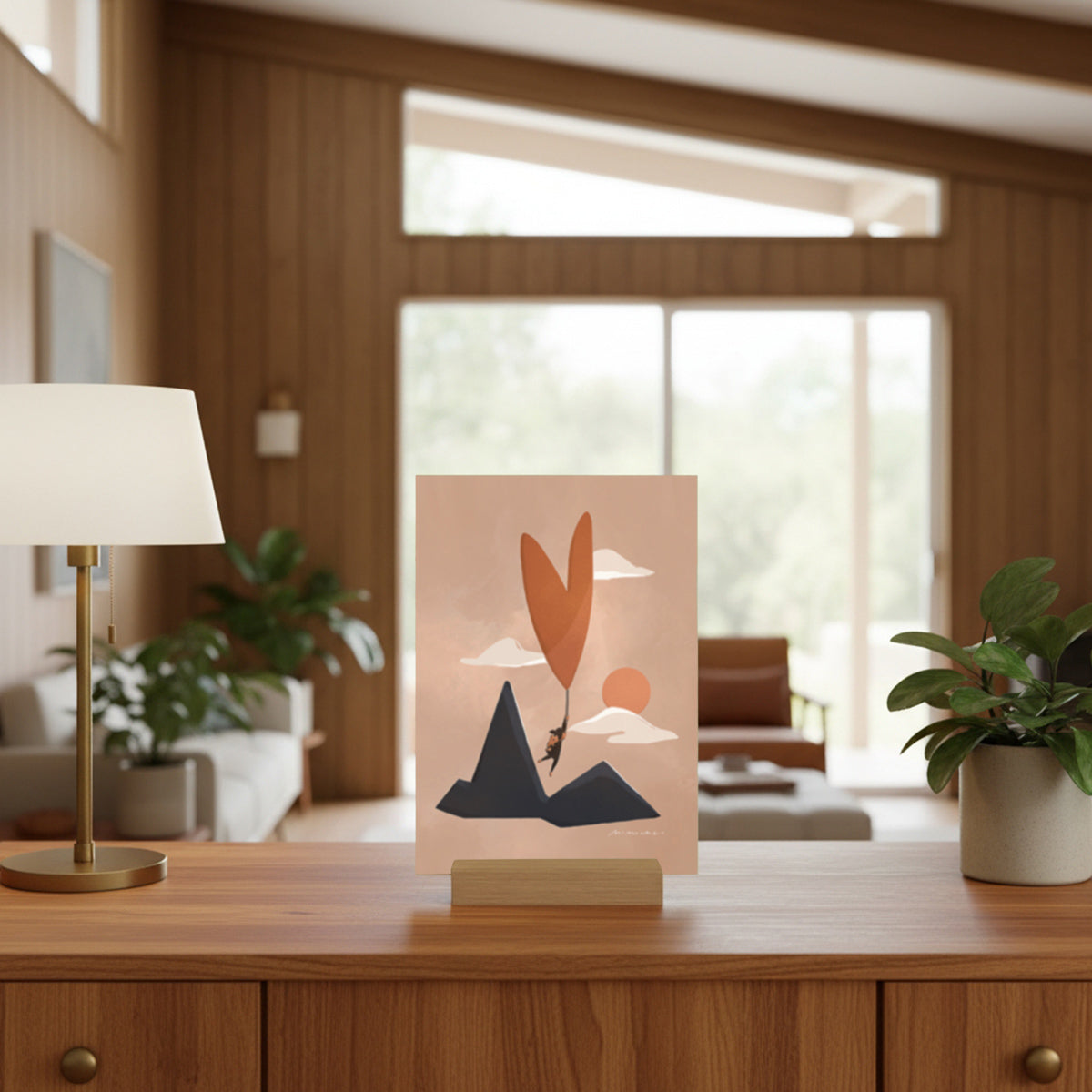Art print with a heart shaped balloon and pink background  on a wooden table in a living room.