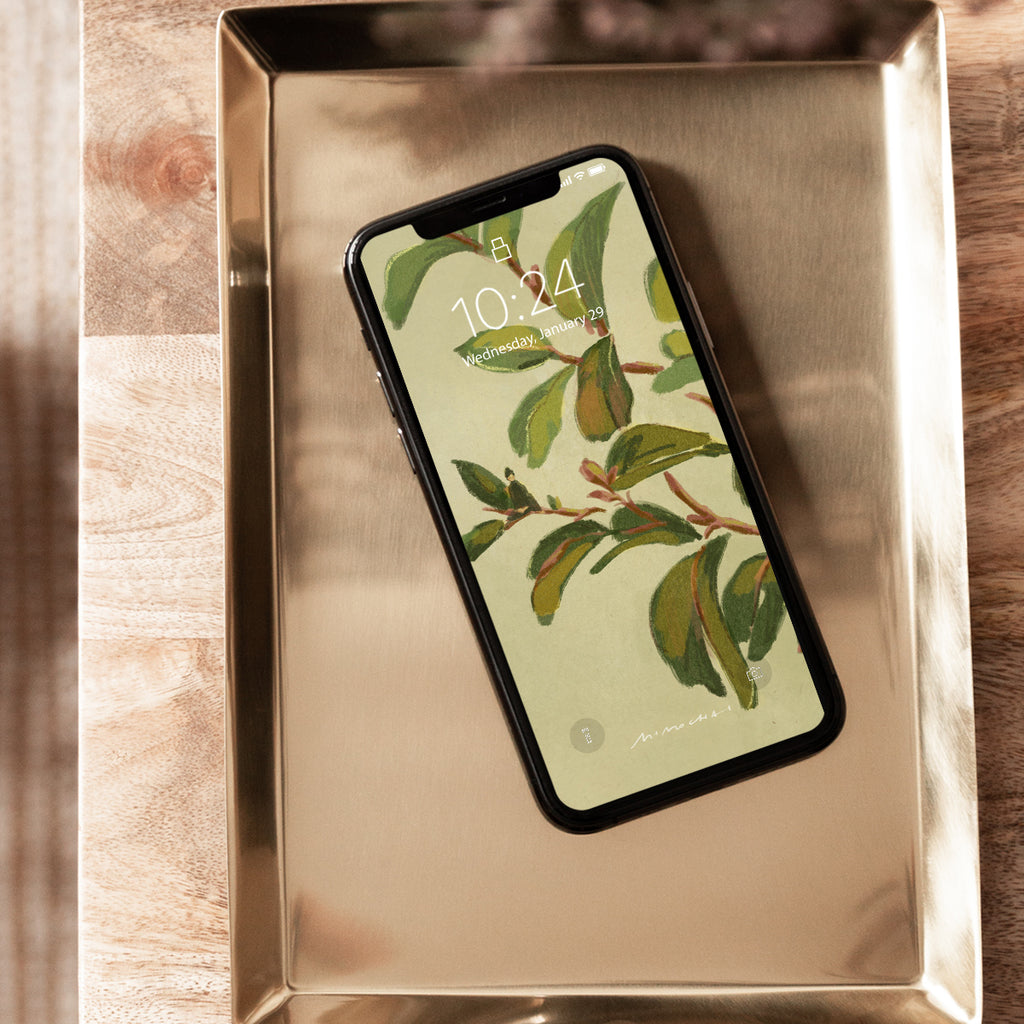 Smartphone with a leafy green lock screen on a metallic tray