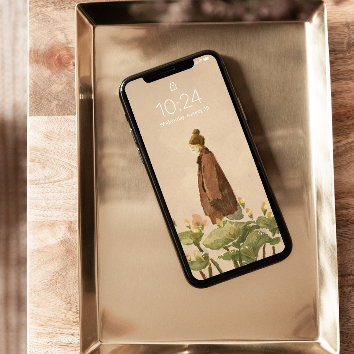 Phone with a Mimochai Lotus Walk nature-themed wallpaper on a metallic tray