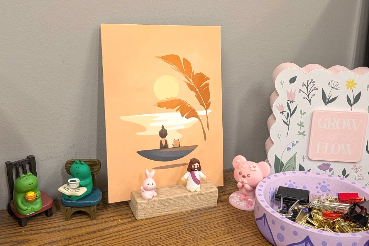 Collection of small figurines and decorative items on a shelf with a sunset painting in the background.