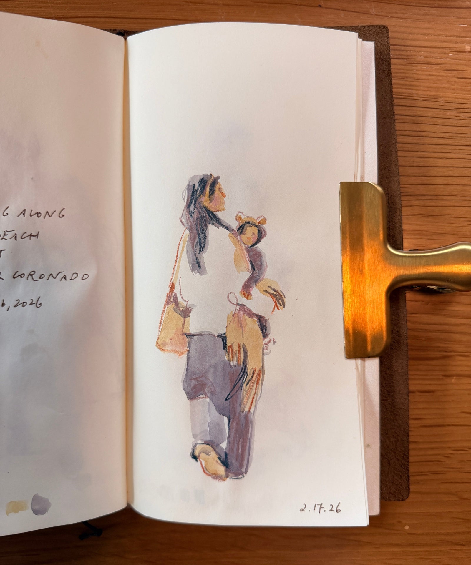 Open sketch book with illustrations of mother and child on a wooden surface