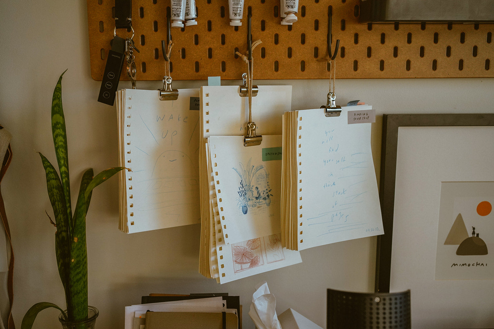 Sketchbook paper and sketches hanging from a bulletin board by Mimochai