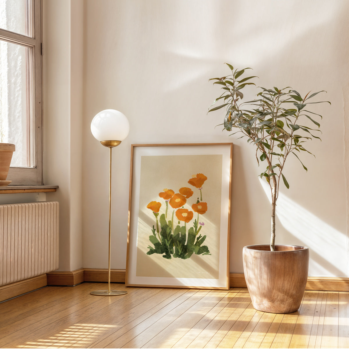 Modern interior with a plant, floor lamp, and framed Mimochai Poppy artwork on a wall.