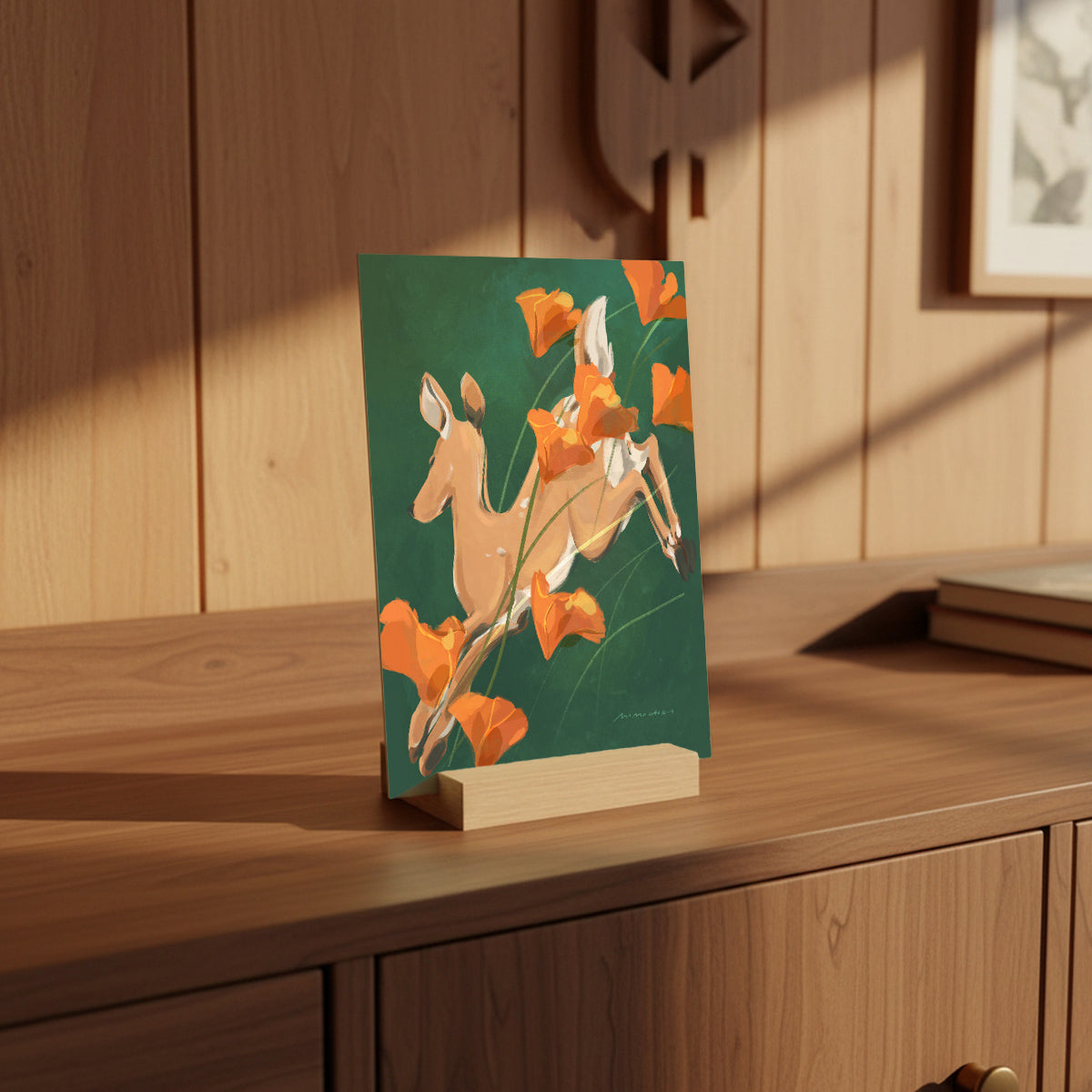 Card with a jumping deer and flower design on a wooden surface