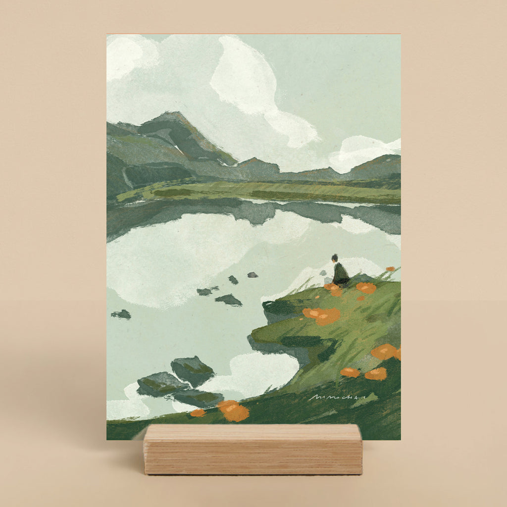 Small art print of a landscape with a lake, mountains, and a person on a rock - Cute nature art print for desk - Mimochai