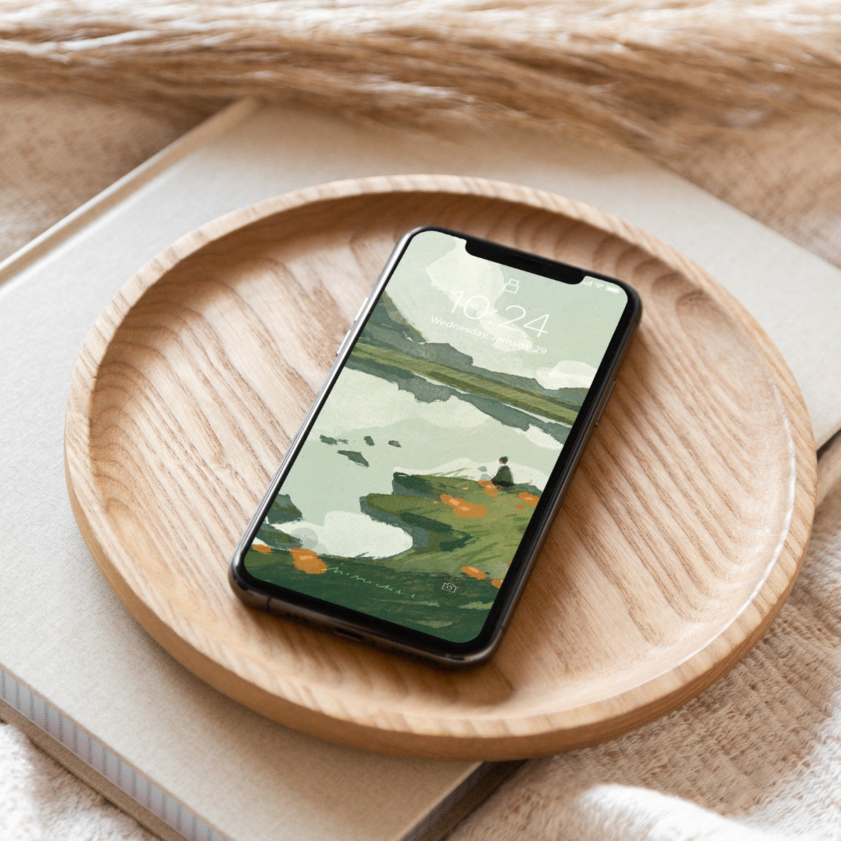 Smartphone with a scenic lake and mountains wallpaper displayed on a wooden plate
