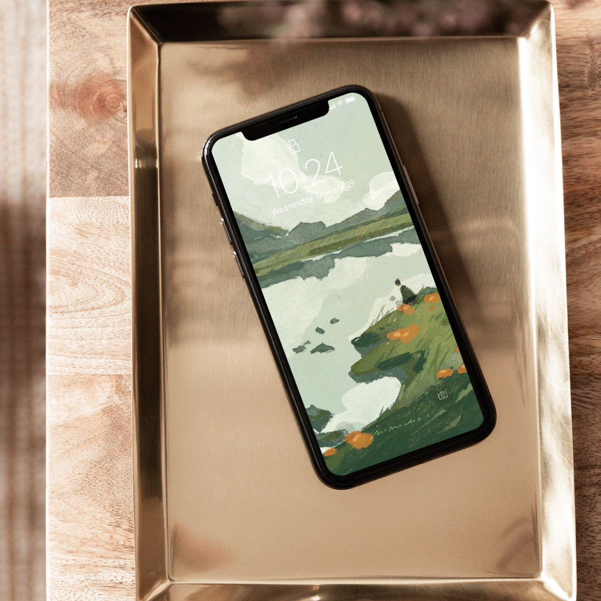 Smartphone with nature-themed lake and mountains wallpaper on a metallic surface
