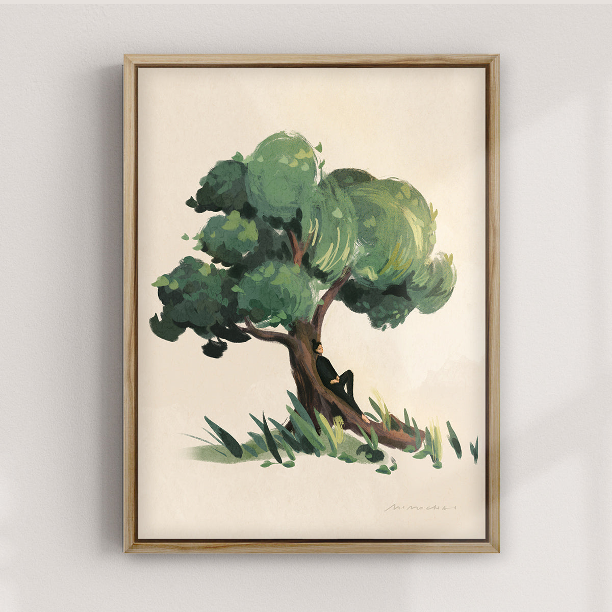 Framed canvas artwork of a tree with a person sitting under it on a plain wall.