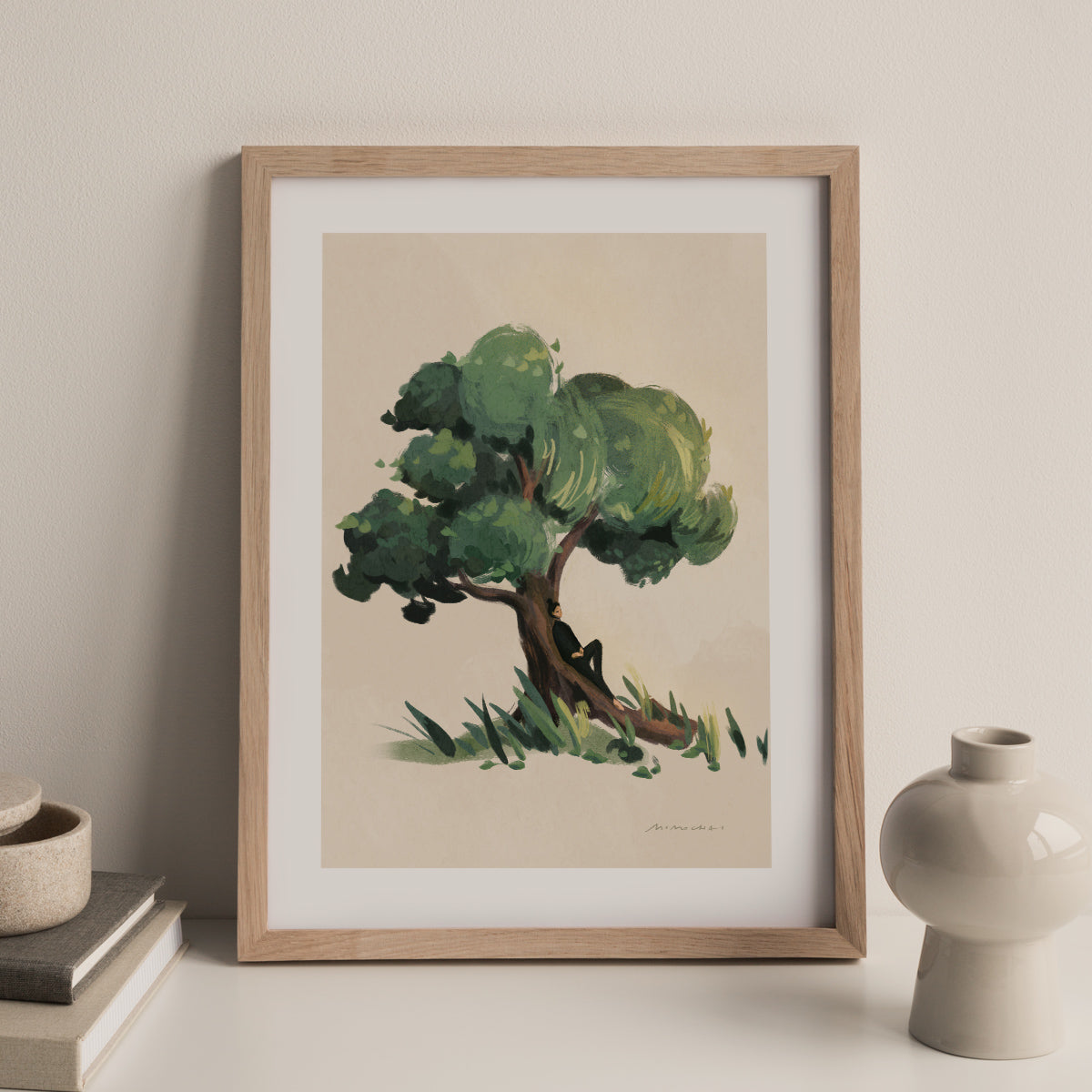 Framed artwork of a tree on a beige wall with decorative items.