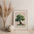 Framed artwork of a tree next to a vase with pampas grass on a textured surface.