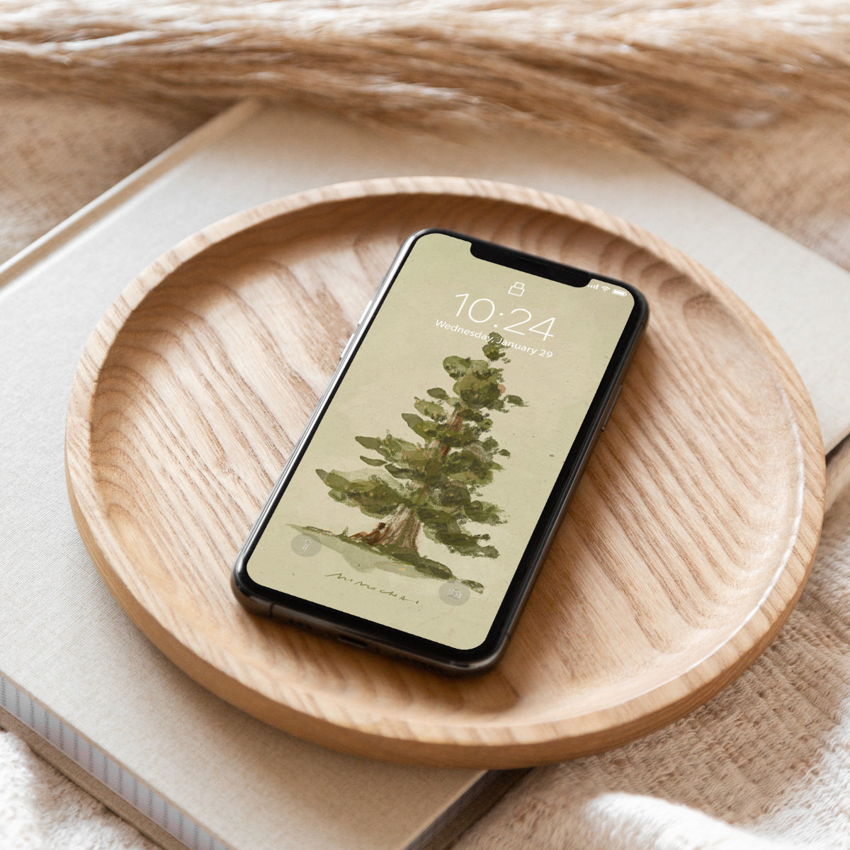 Smartphone with a nature-themed tree wallpaper on a wooden plate